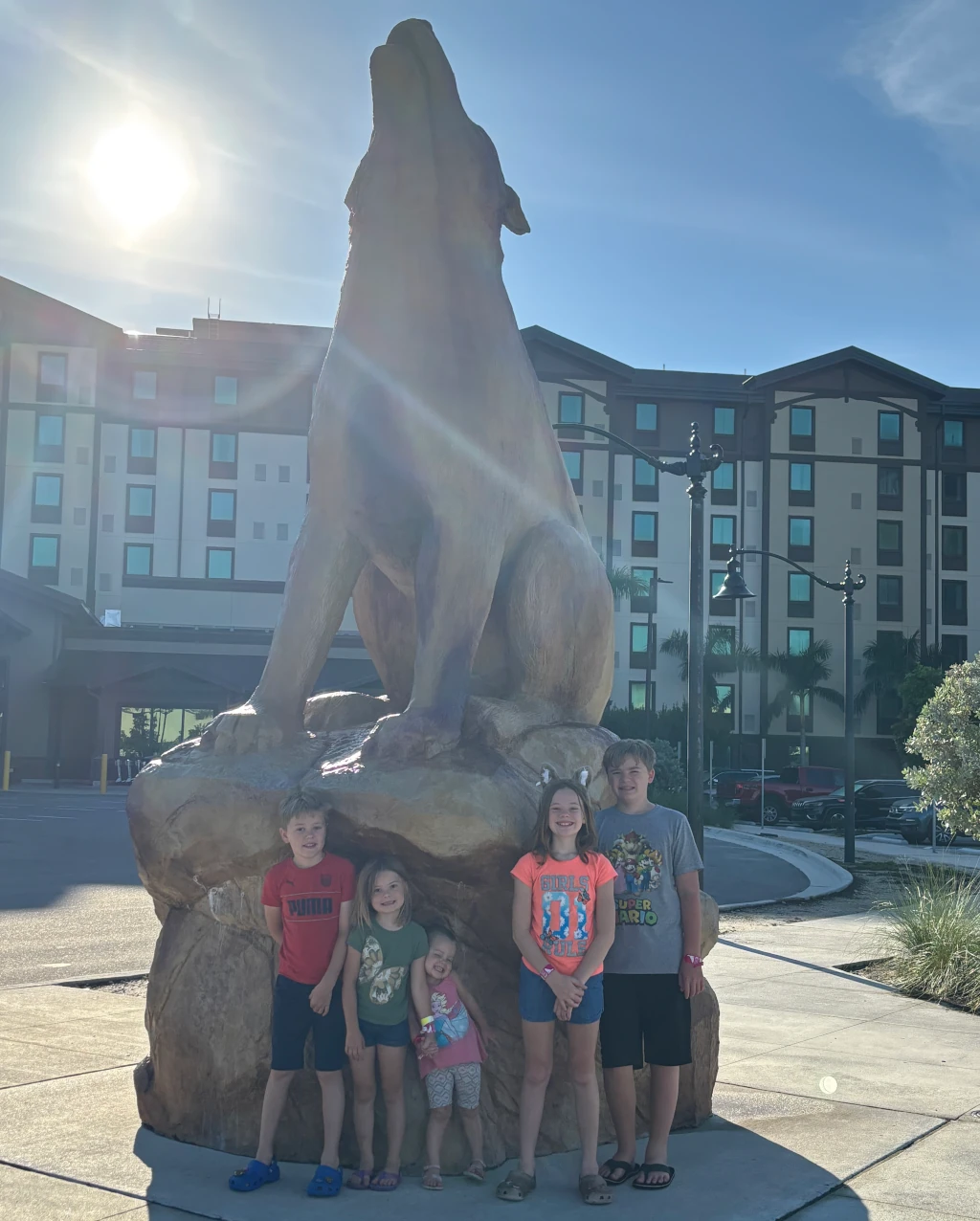 Kids posing by a wolf statue