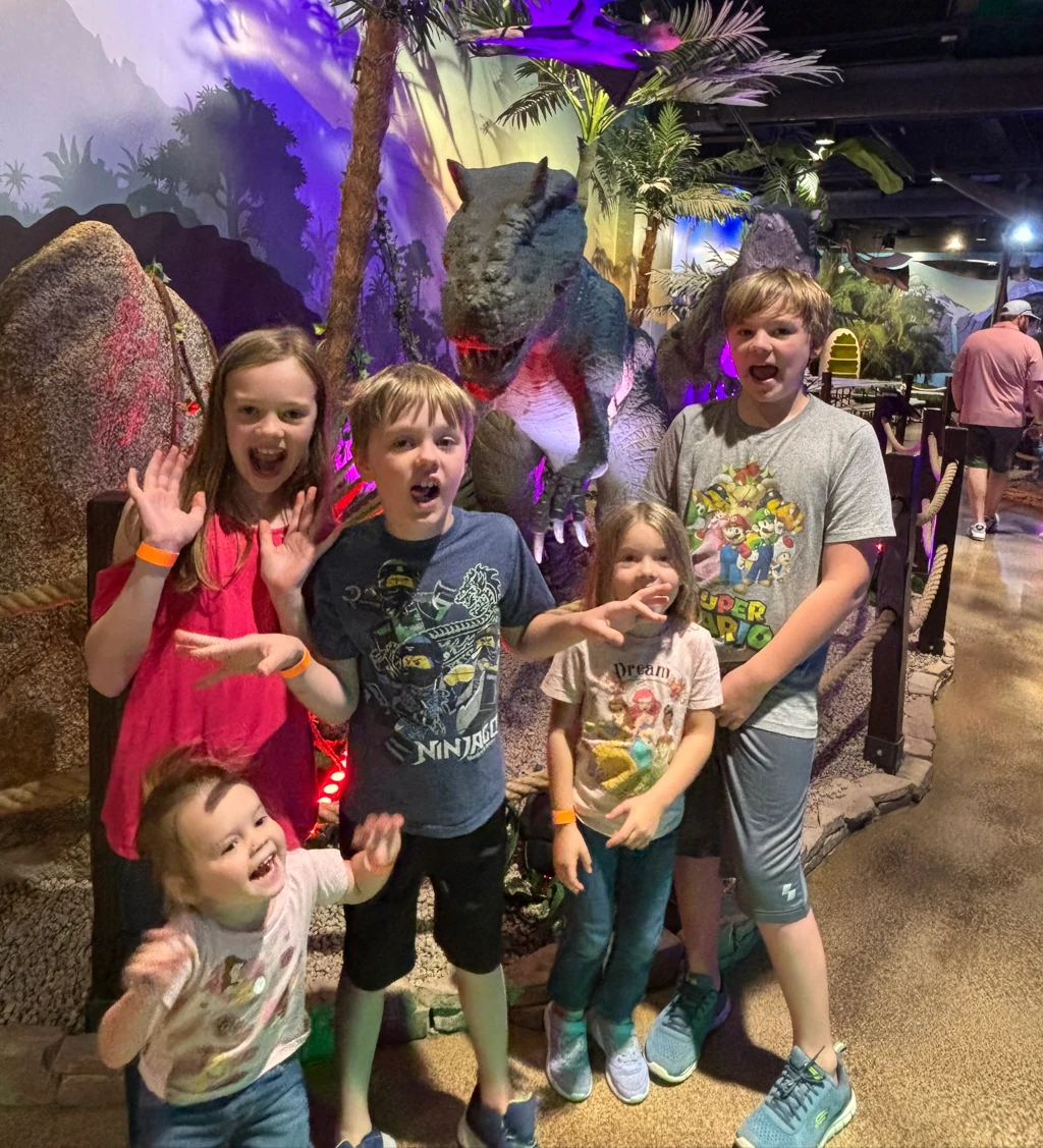 Kids posing in front of a dinosaur statue