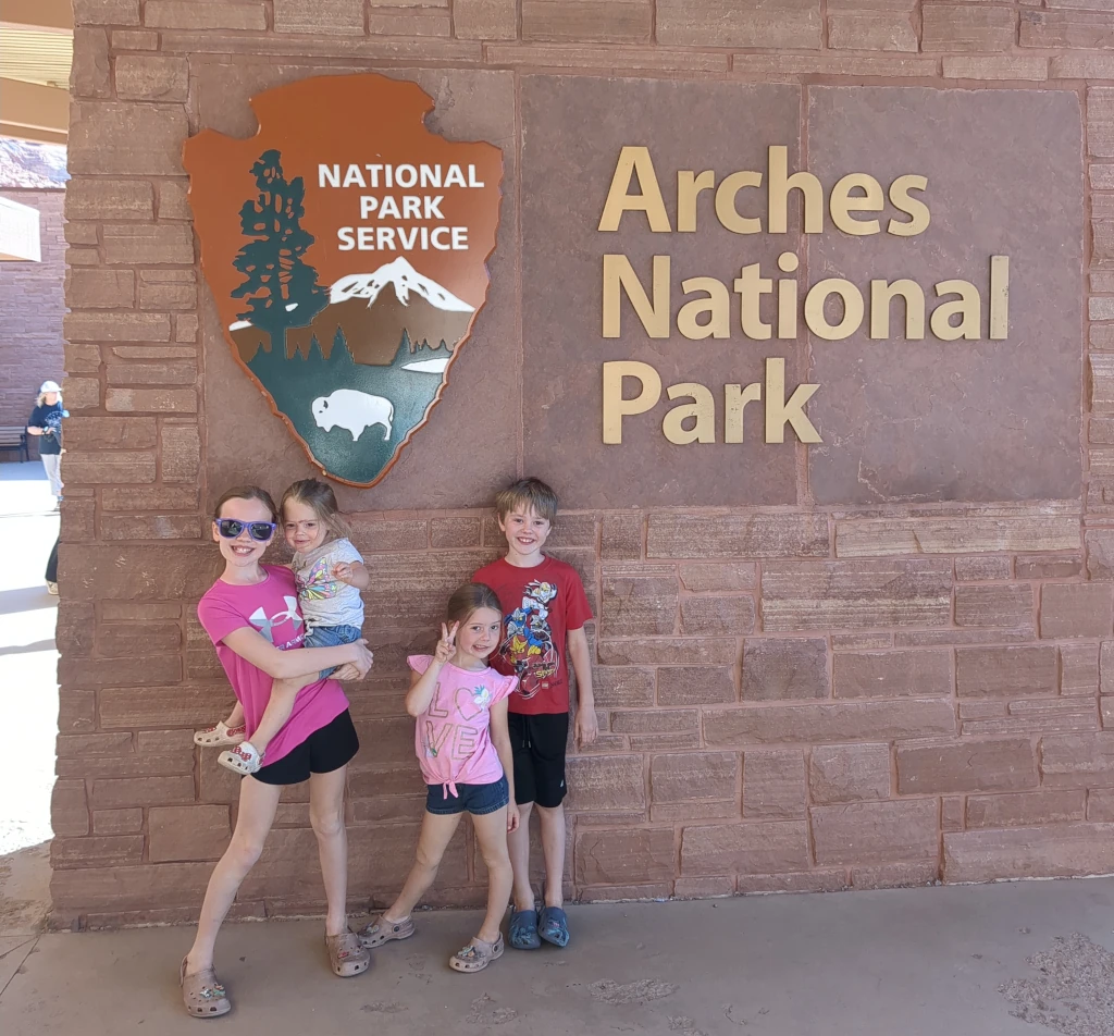 Kids posing in front of the Arches National Park sign