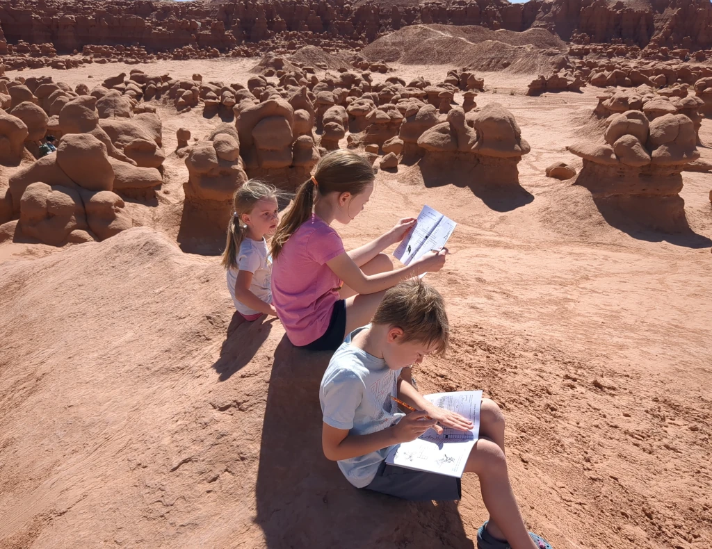 Kids working on notebooks beside various shaped rocks