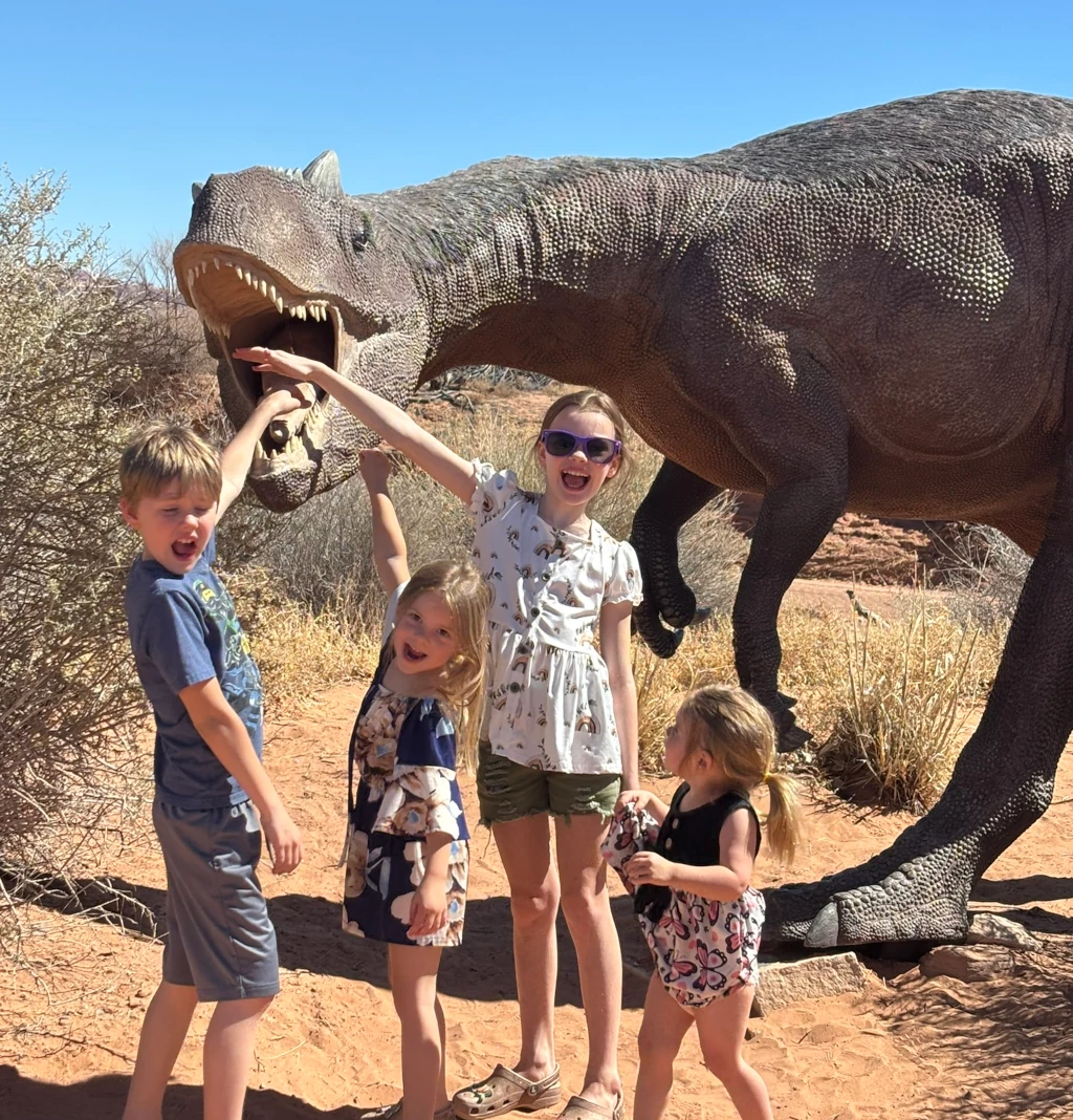 Kids sticking their hands in a fake dinosaur's mouth