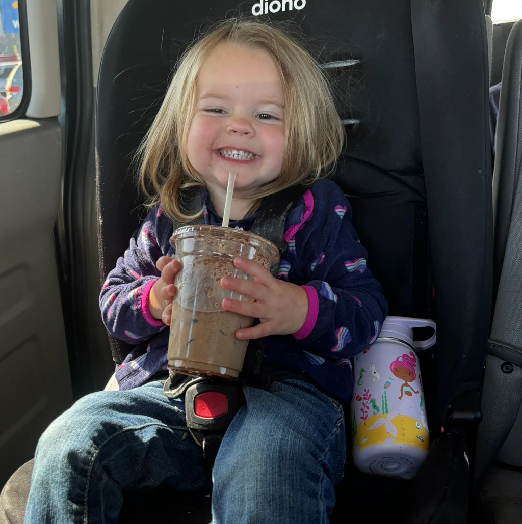 A little girl holding a coffee drink