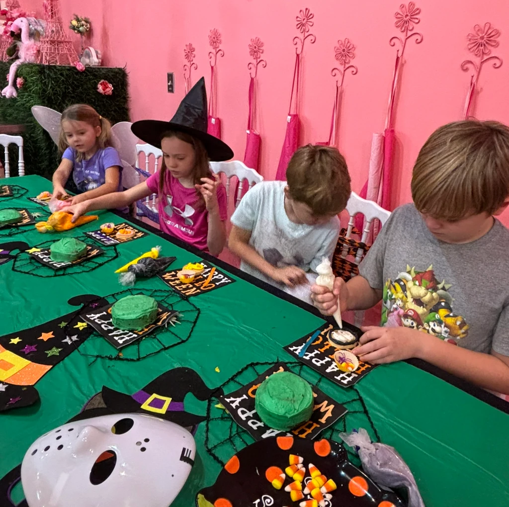 Kids decorating cakes at a Halloween themed table