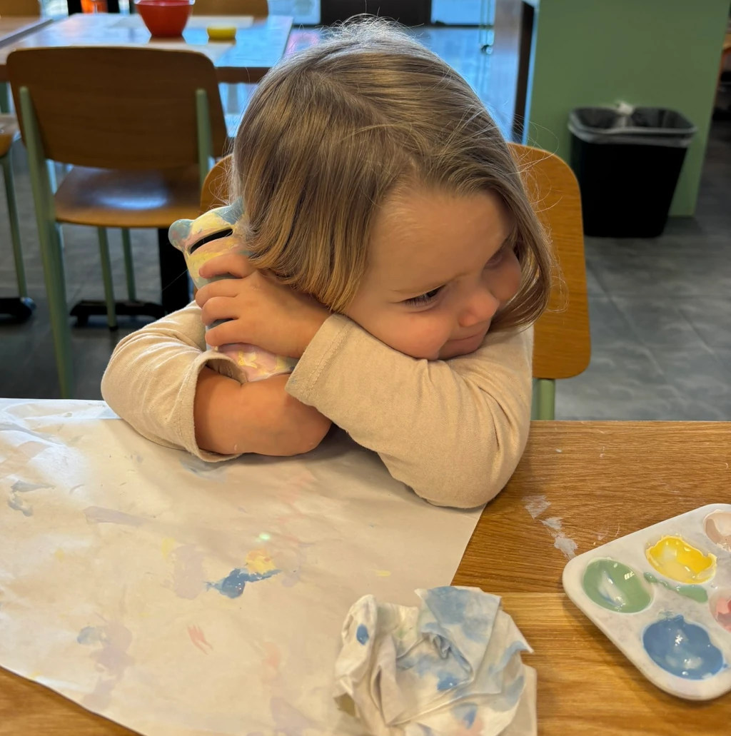 A little girl hugging a hippo-shaped pottery piece