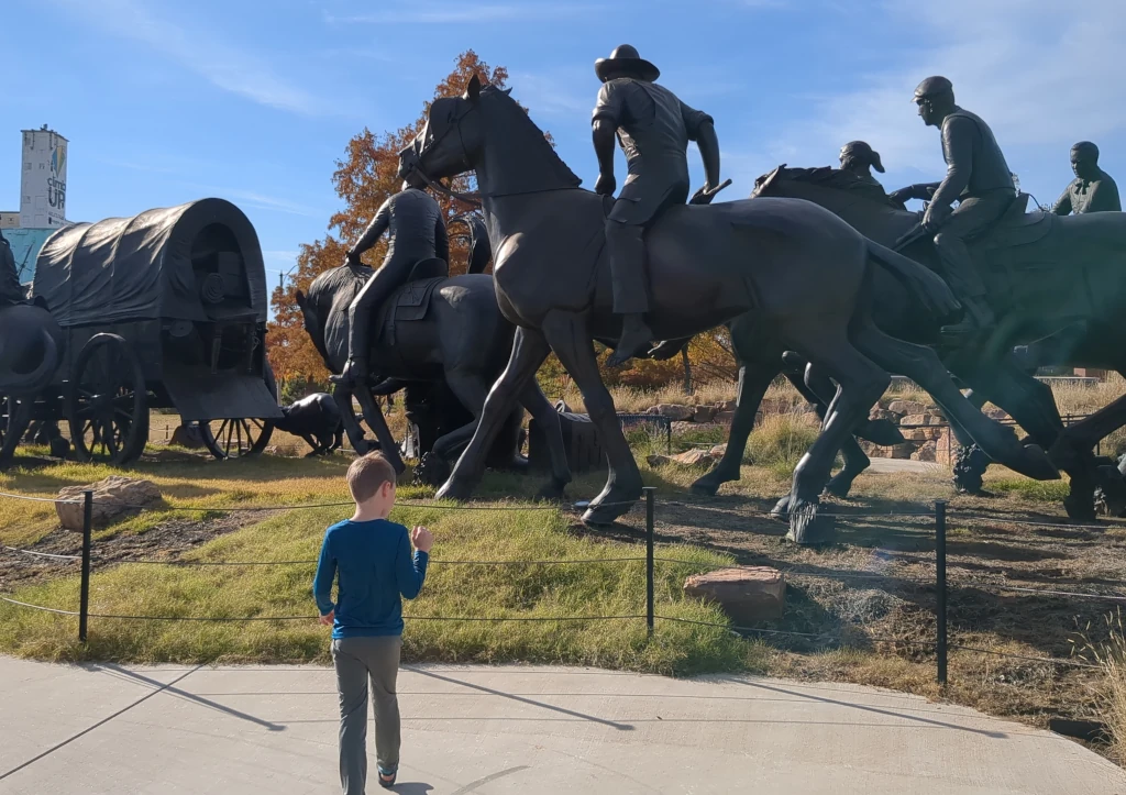 A boy looking at large bronze sculptures