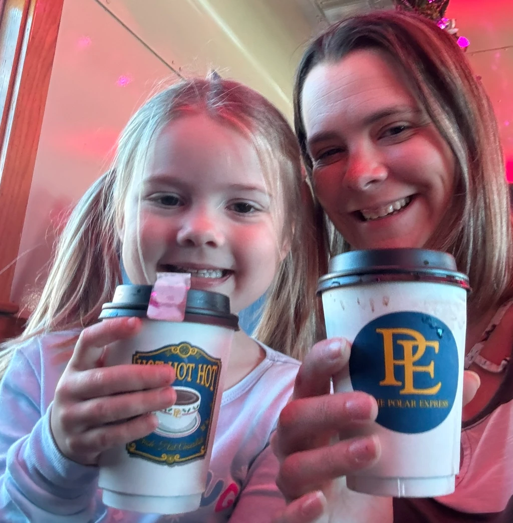 A mom and her daughter holding cups of hot chocolate