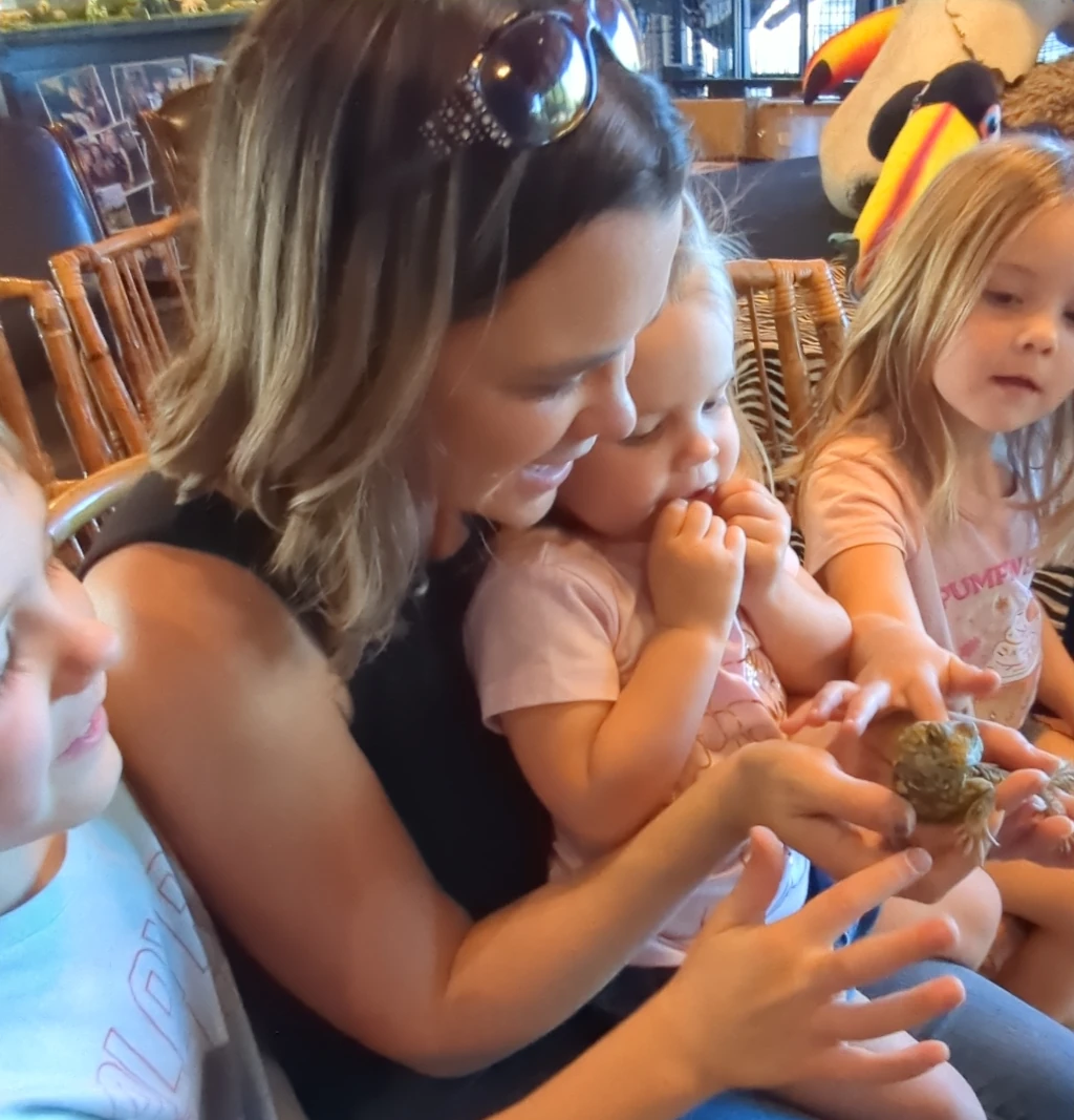 A family looking at a small lizard