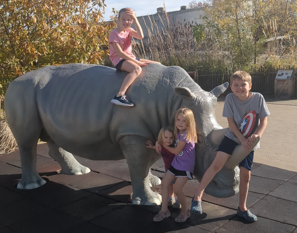 Kids posing on and around a rhino statue