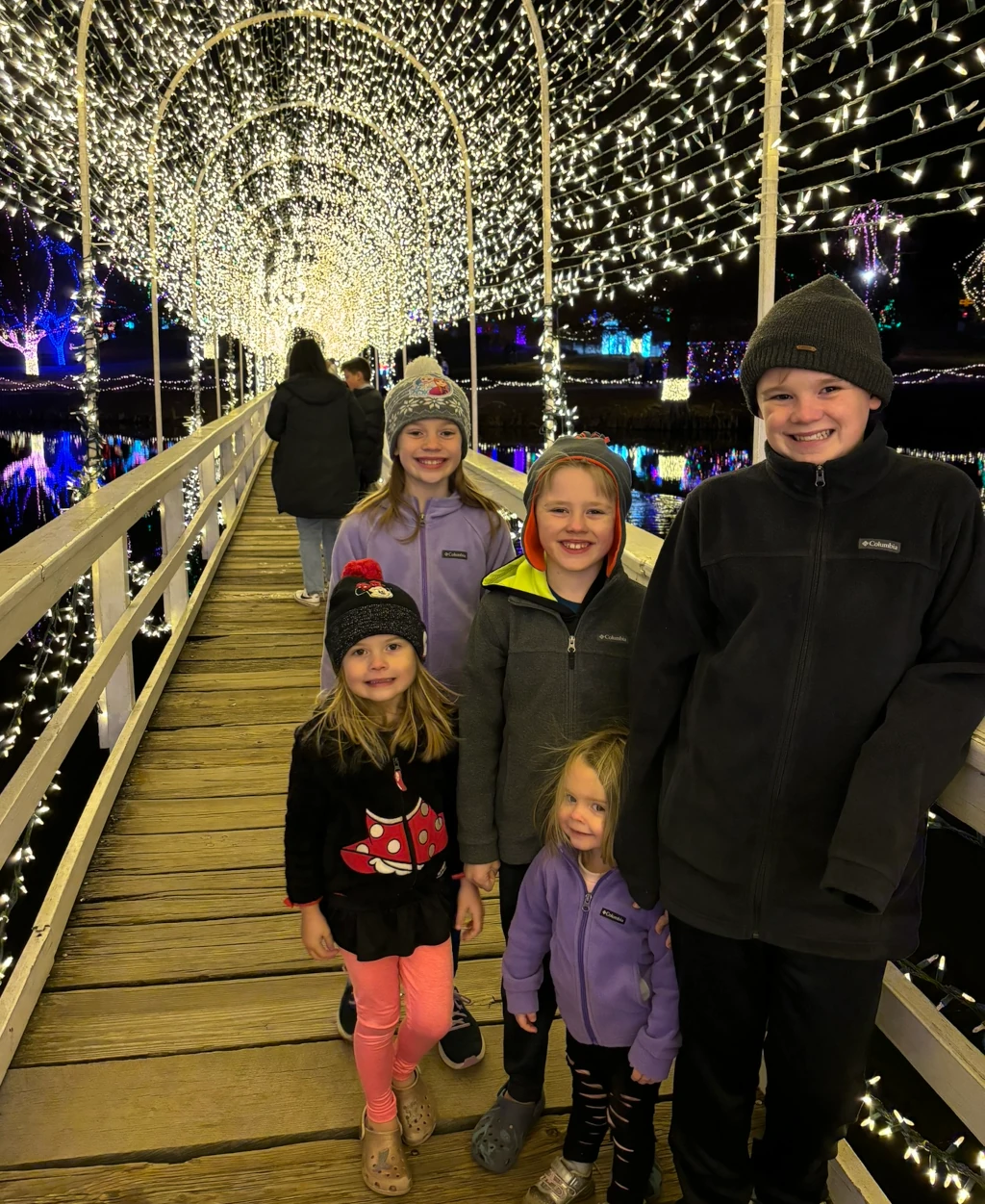 Kids standing on a bridge covered in lights