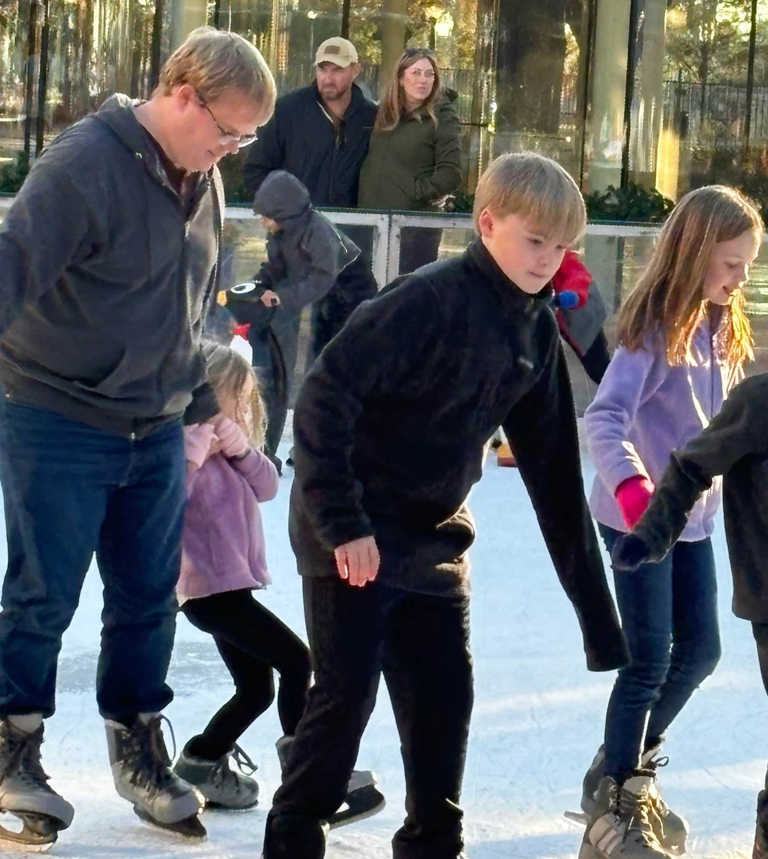 Kids ice skating with their dad