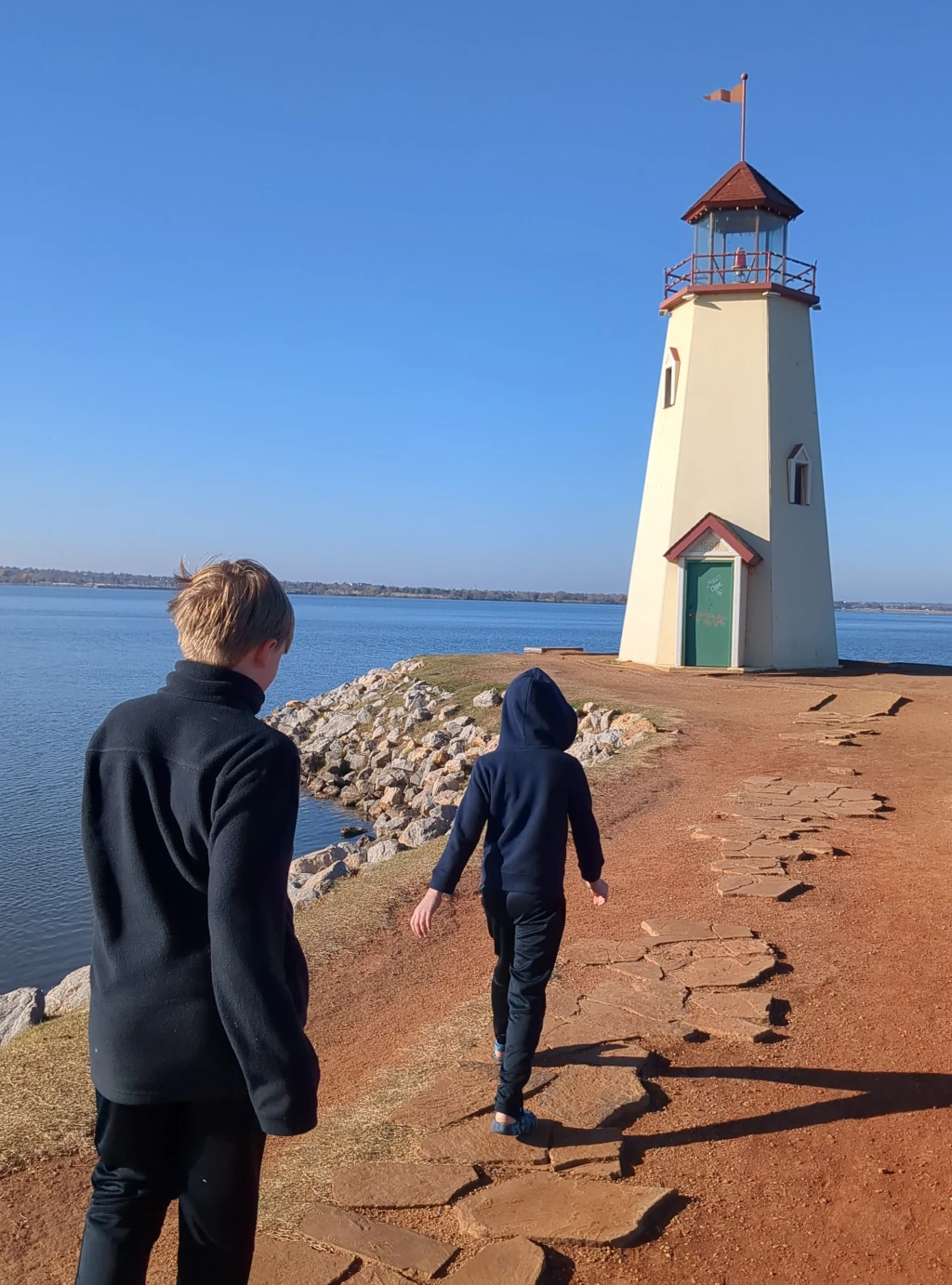 Two boys walking towards a light house