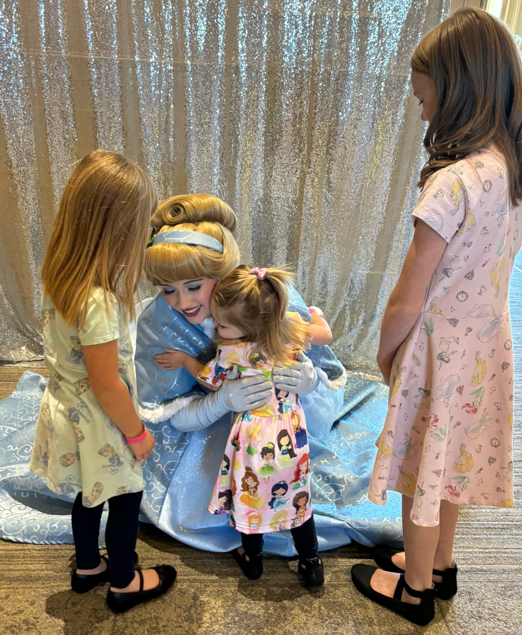 A little girl hugging a lady dressed up like a princess