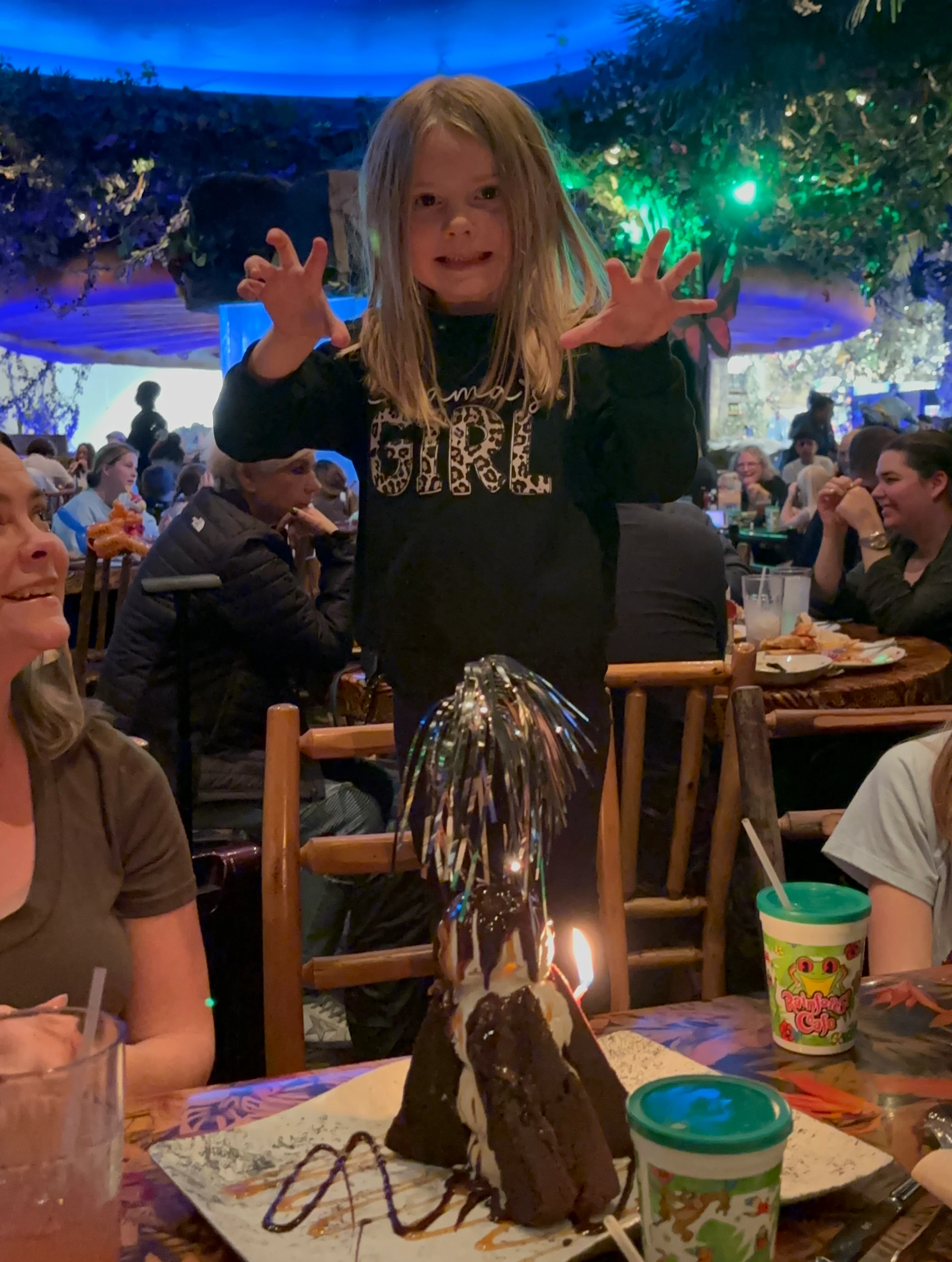 A girl standing on a chair making a tiger pose