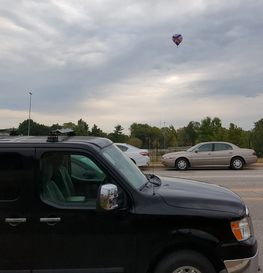 A hot air balloons over a black van