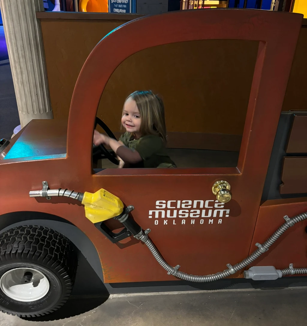 A little girl driving a pretend truck