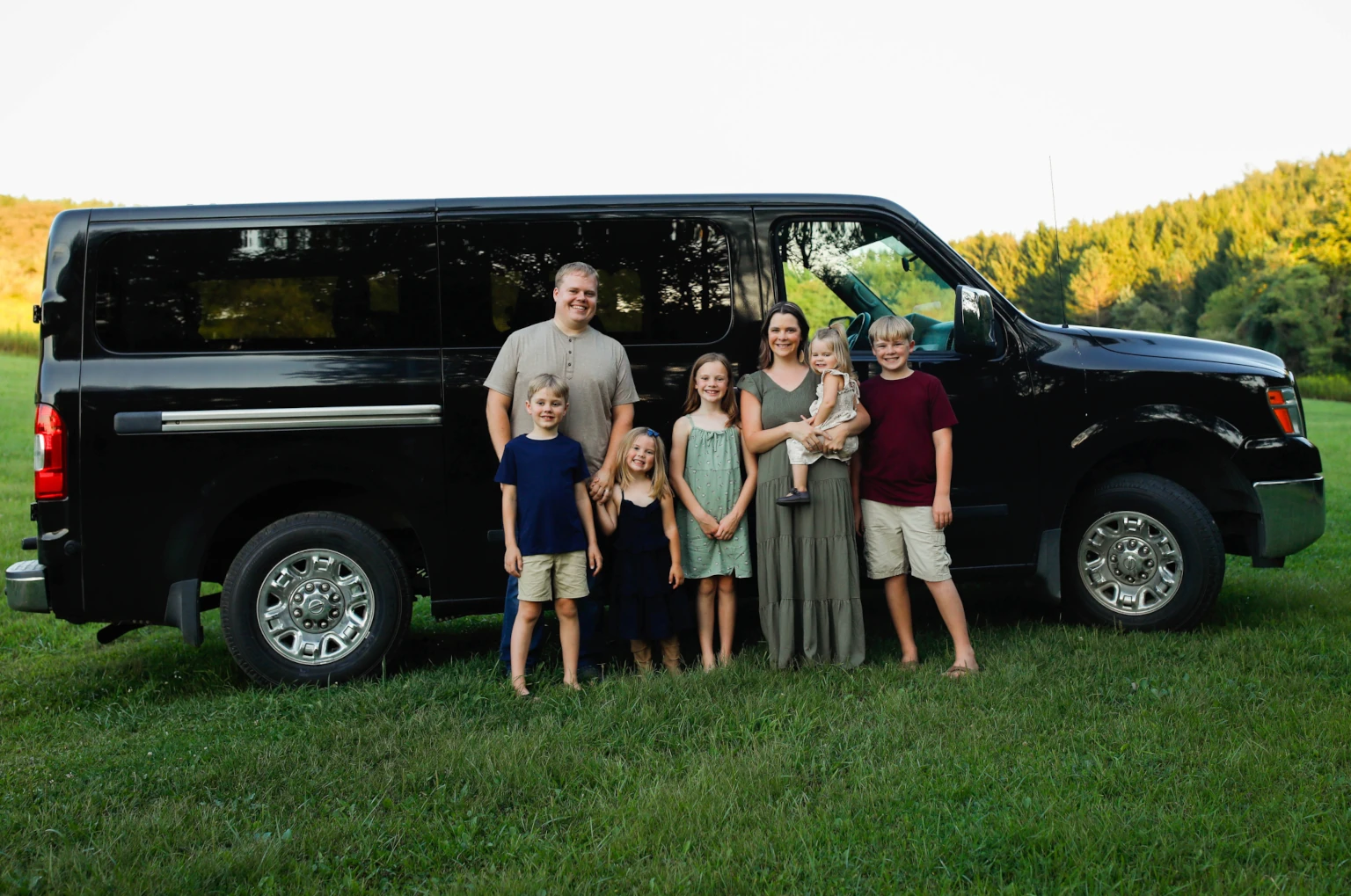 The Douglass family standing in front of a large black van